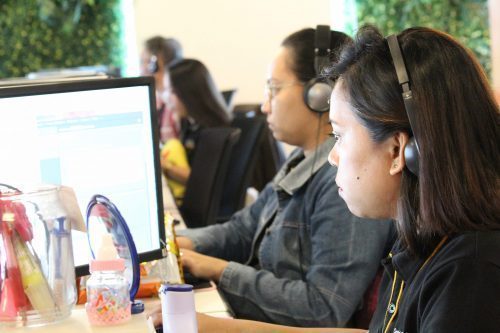 A Female Digital Marketing Employee with a Headset and Computer Monitor