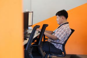 A Male Outsourcing Employee in Checkered doing Content Writing Tasks in front