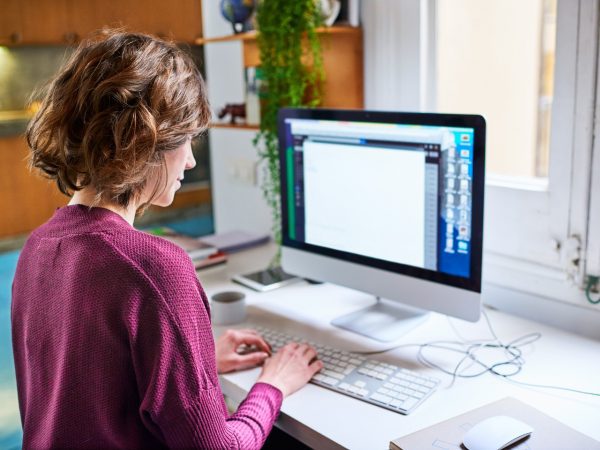 Woman in purple working from home in front of a Computer