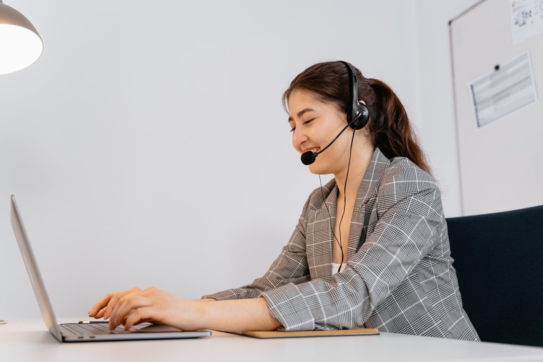 female VA with headset working on a laptop